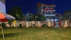 A well-maintained grassy area with a building in the background, a sign reading 'SHIVAALIK,' and a few umbrellas. - shivaalik (Varanasi)