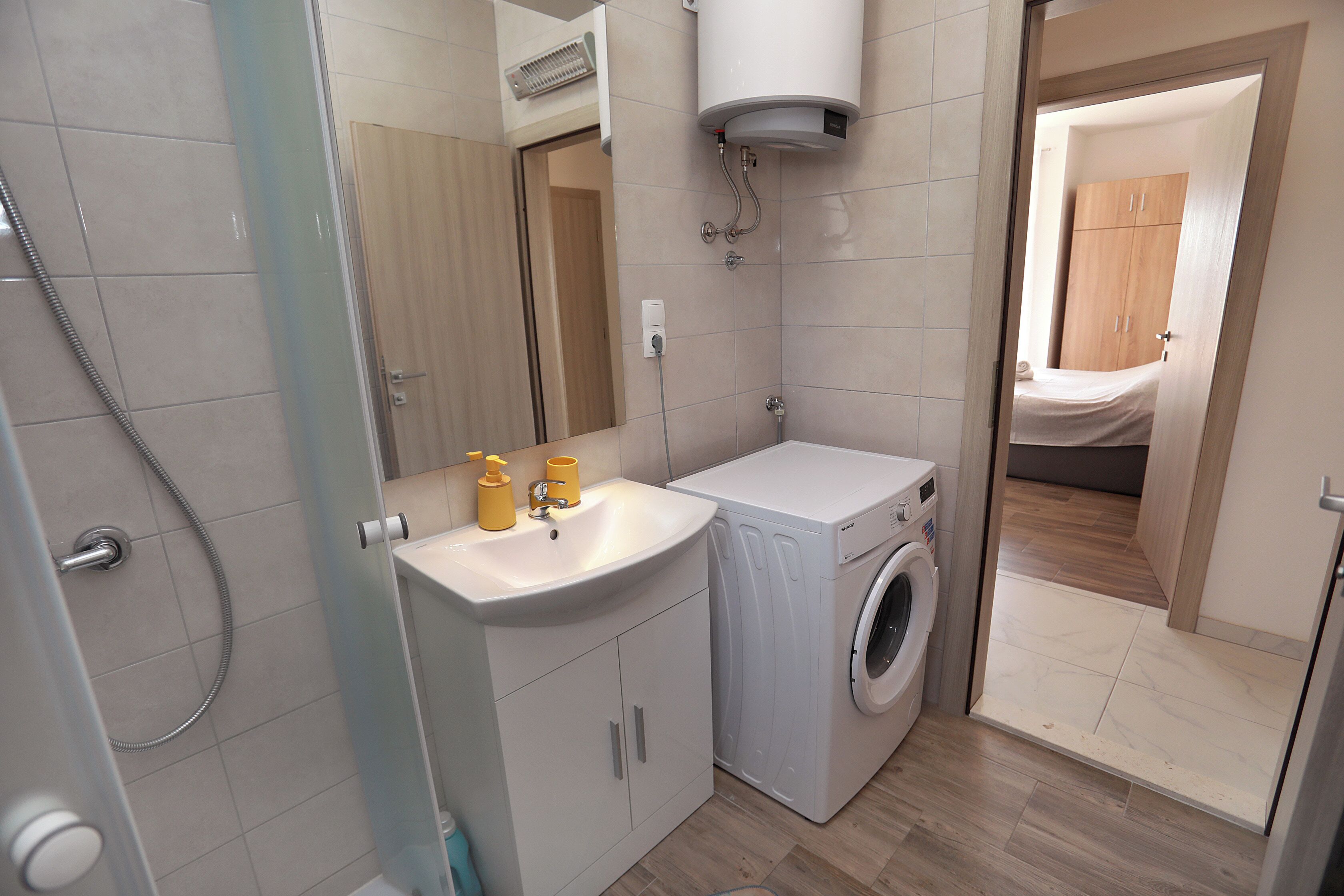 Ein kleines Badezimmer mit Waschmaschine, Waschbecken und Spiegel.