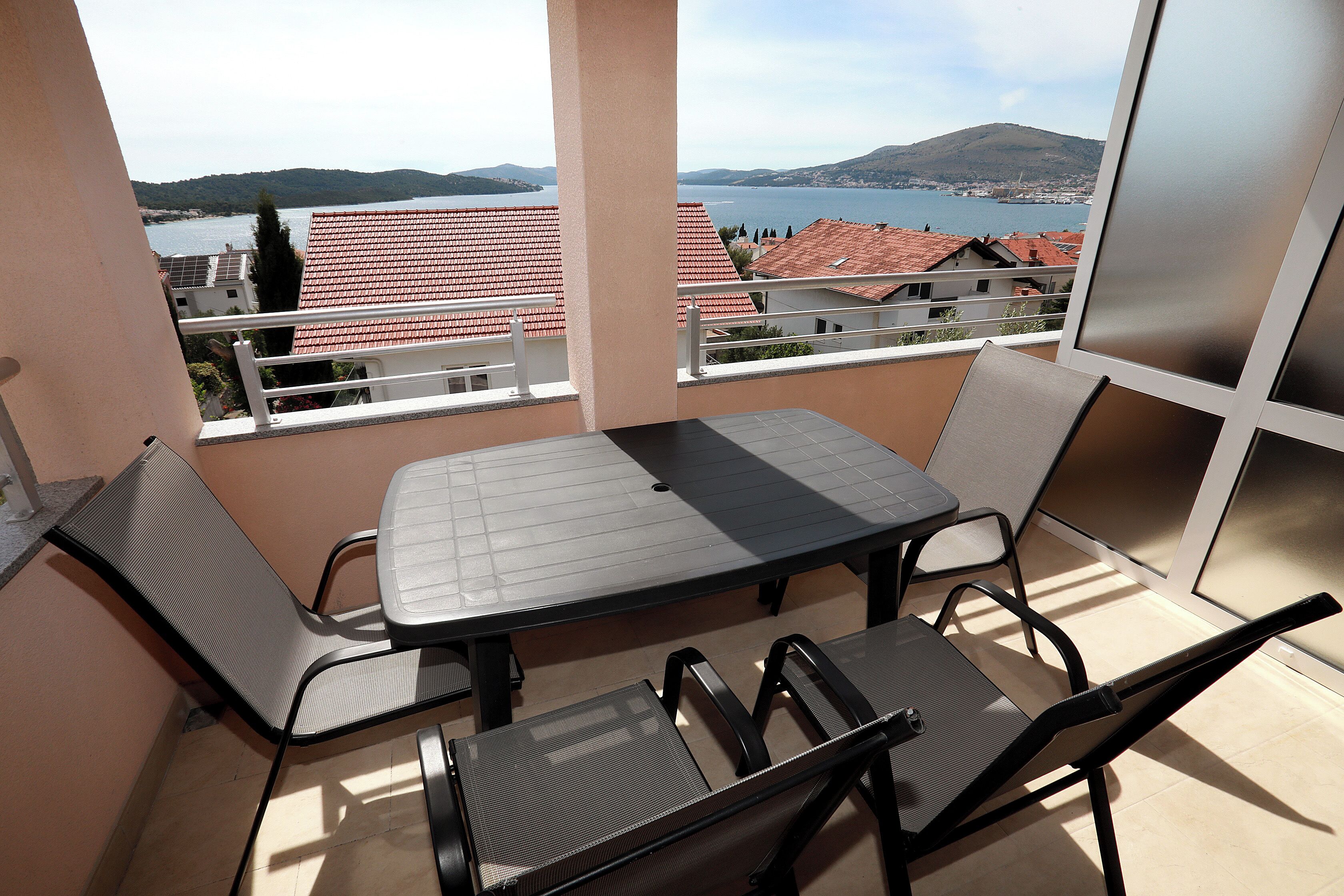 Un balcón con mesa y sillas, con vistas a un lago y edificios.