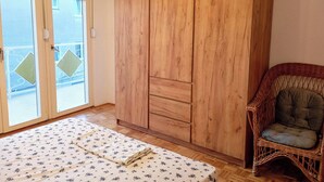 Ein Zimmer mit einem Holzschrank, einem Korbstuhl und einem Bett mit floralem Überwurf.