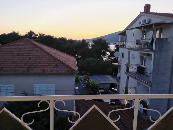 Ein Wohngebäude mit rotem Ziegeldach, Satellitenschüsseln und einem Balkon mit weißer Brüstung.