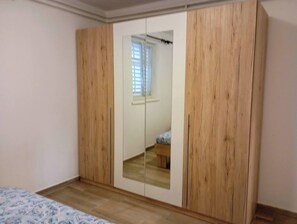 A bedroom with a wooden wardrobe, a bed with a patterned bedspread, and a window with blinds. - Sunny apartment in Trogir (Trogir)