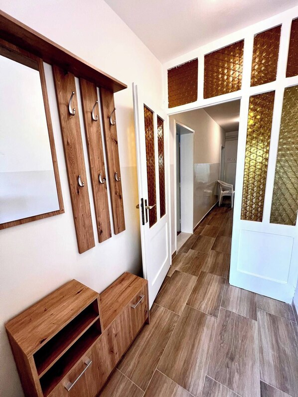 A hallway with wooden flooring, a bench, and a door with decorative panels. - Sunny apartment in Trogir (Trogir)