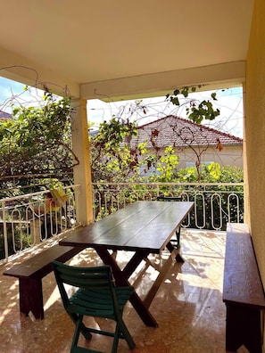An outdoor patio with a table and chairs, surrounded by a white metal fence and greenery. - Sunny apartment in Trogir (Trogir)