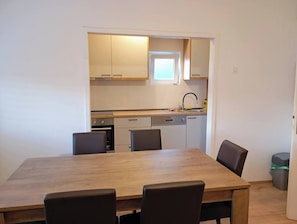 A compact kitchen with a dining area, including a wooden table and chairs, a small window, and basic amenities. - Sunny apartment in Trogir (Trogir)