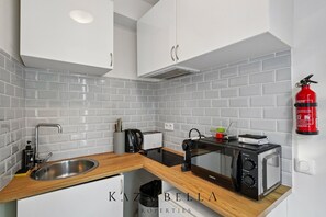 Eine moderne Küche mit weißen Schränken, einer Edelstahl-Spüle, einem Toaster, einem Wasserkocher und einer Mikrowelle.
