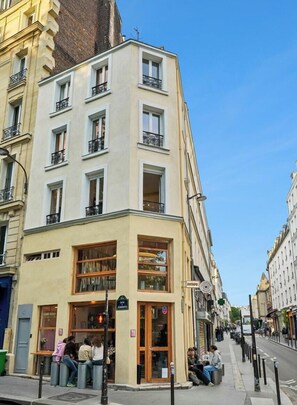Ein Eckgebäude mit Laden im Erdgeschoss, mehreren Fenstern und einer sichtbaren Straße.