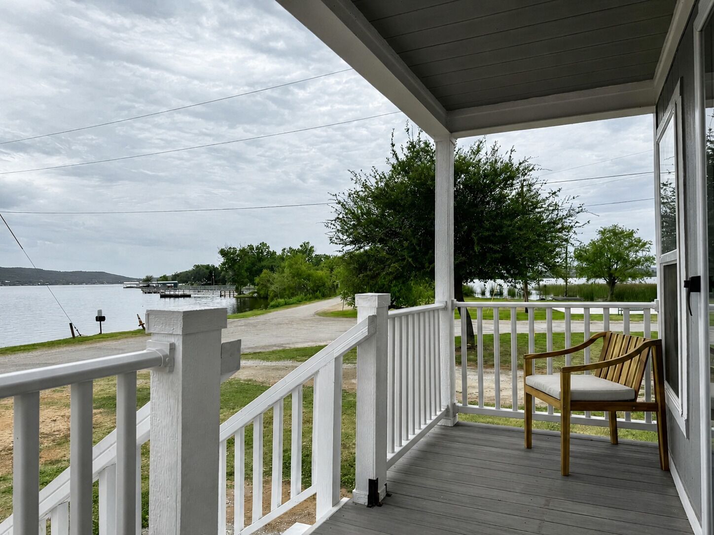 A covered porch with a view of a lake and a dock.