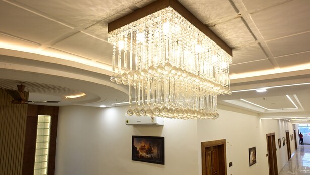 Un pasillo con una gran araña de cristal, obras de arte enmarcadas y una larga galería de puertas.