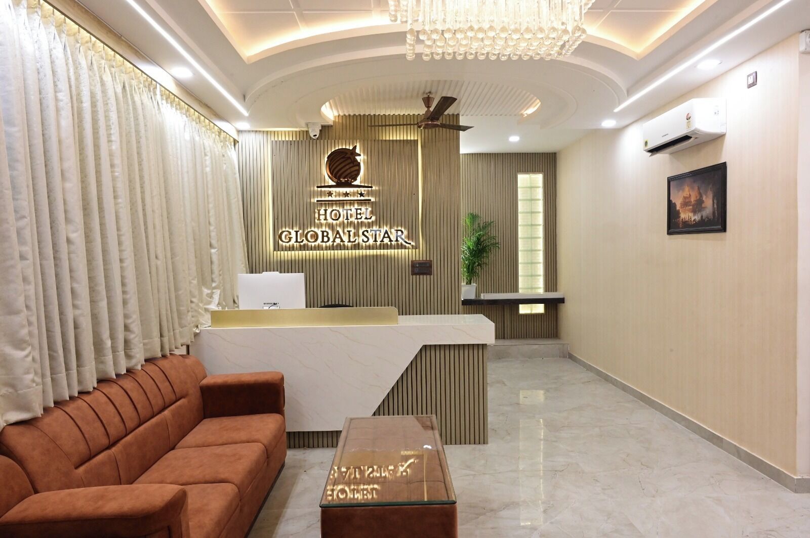 A hotel reception area with a reception desk, a sofa, a coffee table, and a chandelier.
