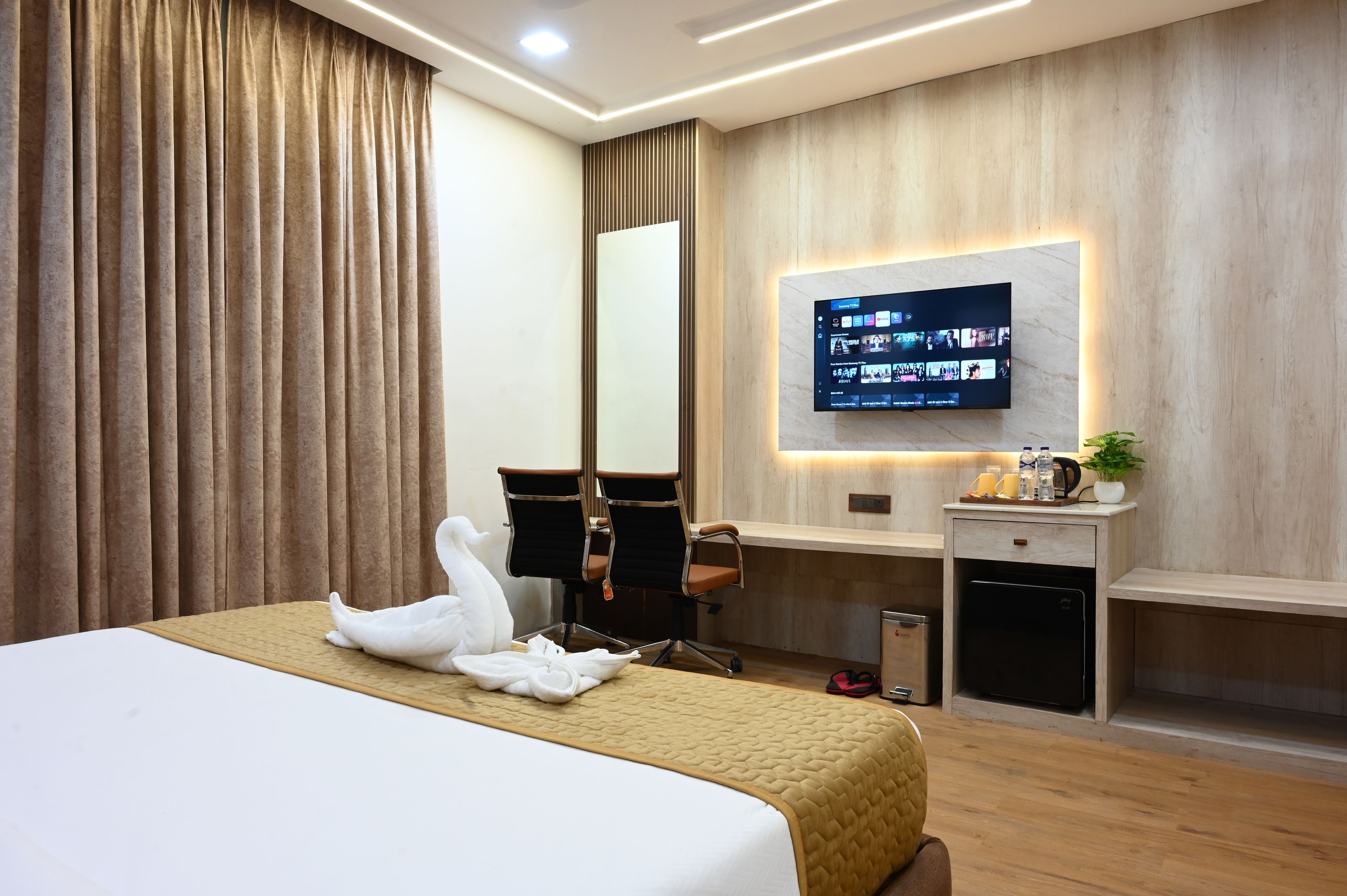 A hotel room with a bed, a desk, a chair, a television, and a mirror.