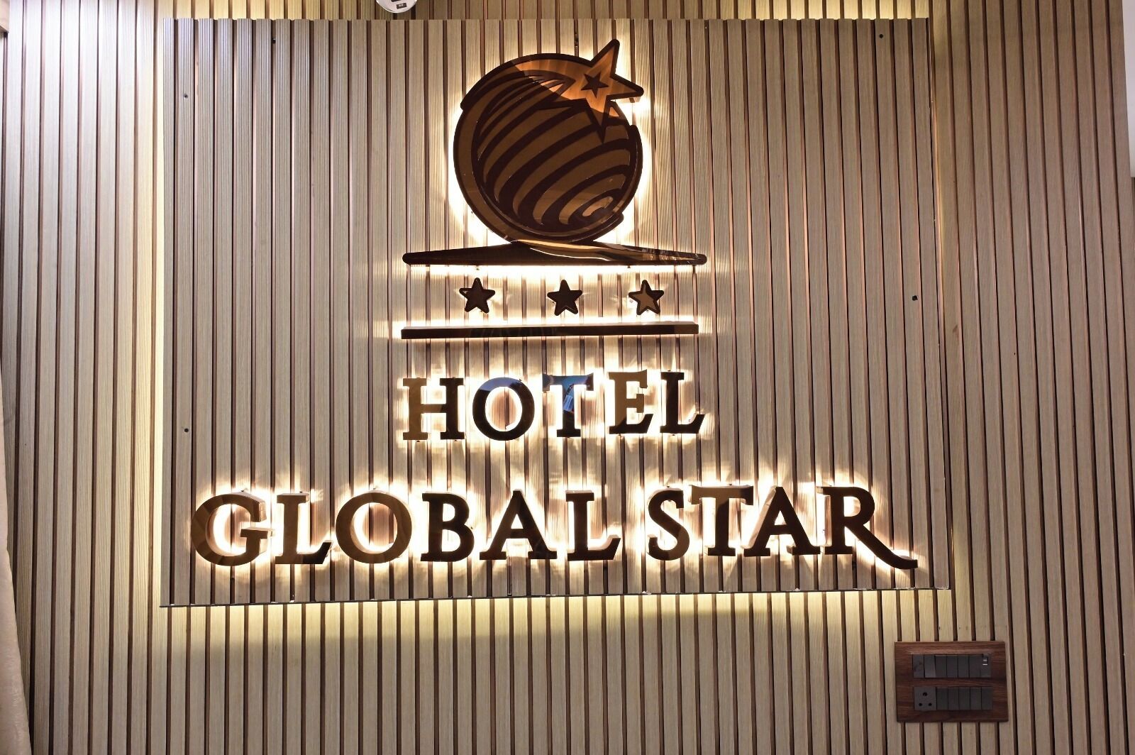 Une enseigne d’hôtel représentant un globe terrestre et des étoiles, ce qui indique que l’établissement a pour thème le monde.