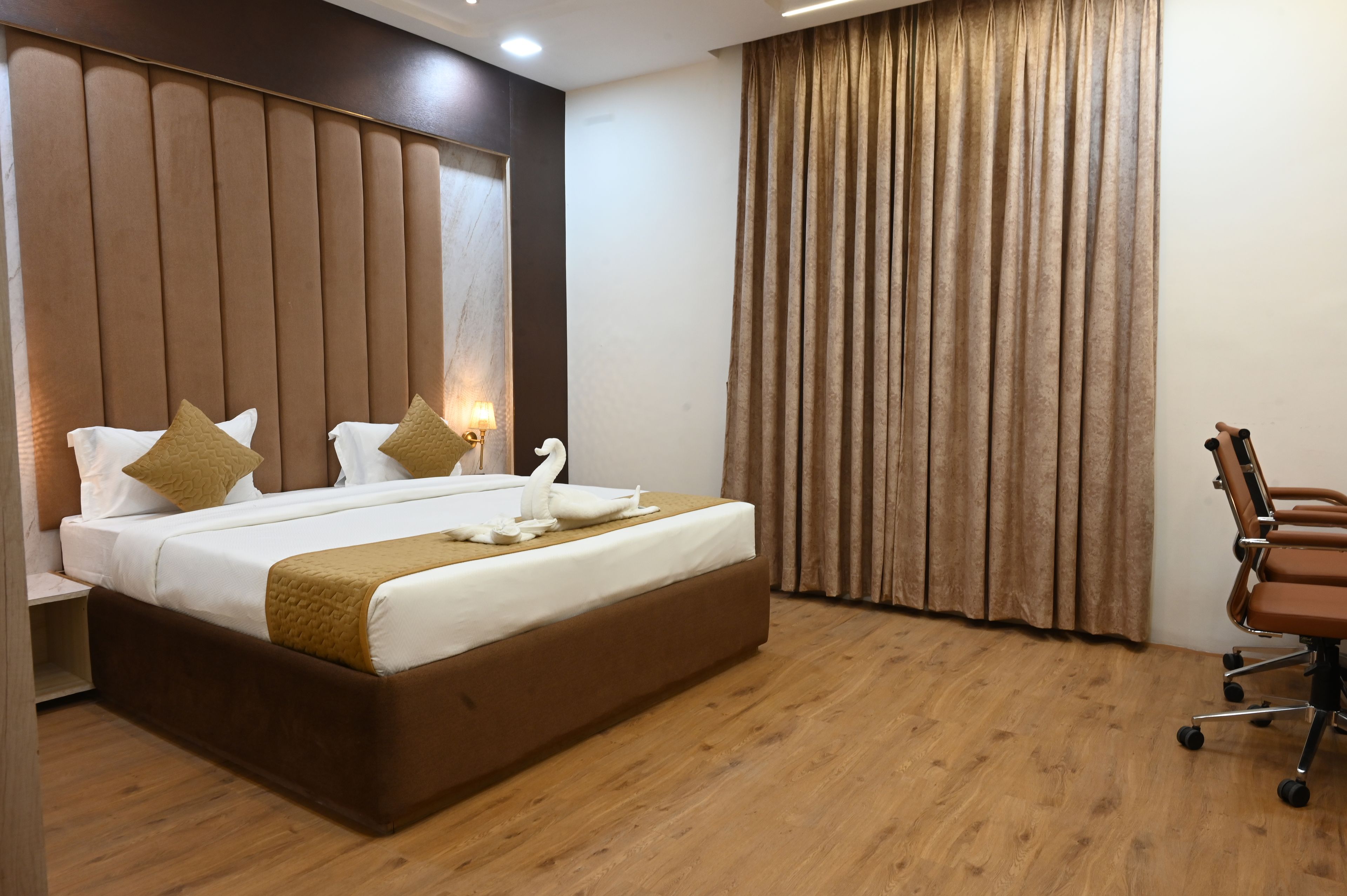 A hotel room with a large bed, a desk, and a chair.