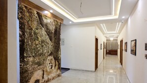 Un pasillo con pared texturizada, suelo de mármol pulido y cuadros enmarcados.