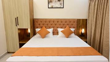 A hotel room with a large bed, a wooden wardrobe, a headboard, and a framed picture on the wall.