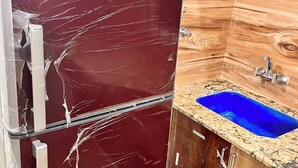 Una cucina con frigorifero, lavello e mobili impiallacciati in legno.