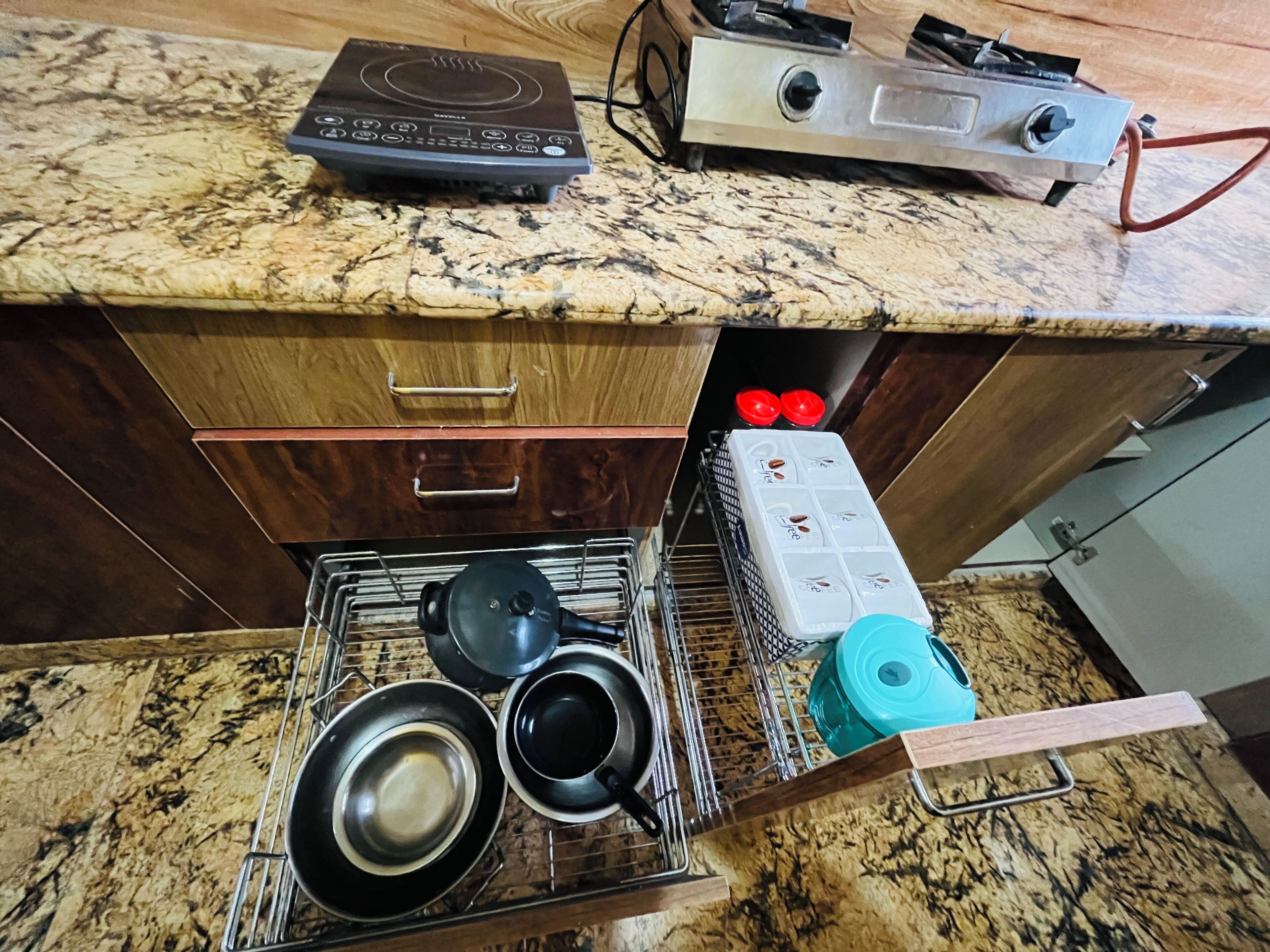 Una cocina con encimera de granito, cafetera, hervidor y tostadora.