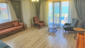 Amplia sala de estar con un sofá, sillones, una mesa redonda de centro y un mueble para televisión.