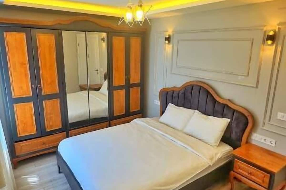 Un dormitorio con cama, mesita de noche, espejo y armario.