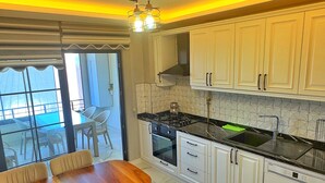 Una cocina moderna con armarios blancos, una mesa de comedor con sillas, una estufa y un lavavajillas.