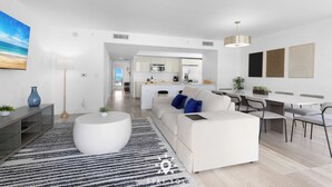 Een moderne woonkamer met een bank, salontafel en eethoek.
