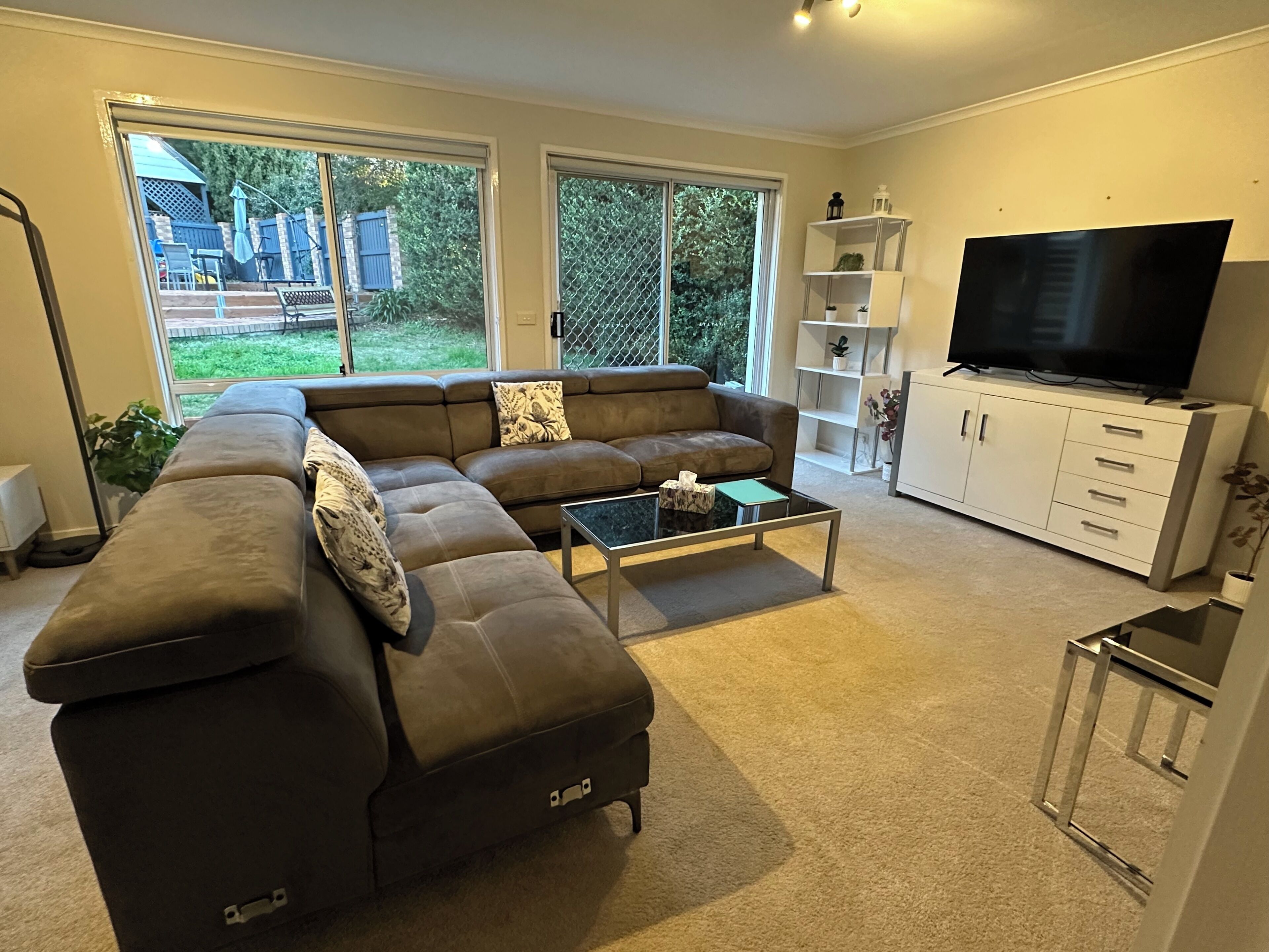 Ein Wohnzimmer mit Ecksofa, Couchtisch, Fernseher und Bücherregal.
