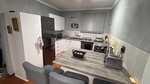 A compact kitchen with a refrigerator, stove, sink, and a small dining area with a table and chairs.