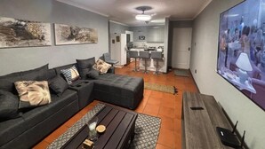 A modern living room with a sectional sofa, a coffee table, and a flat-screen TV.