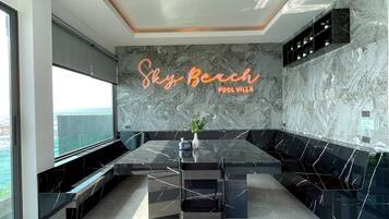 A modern kitchen with a marble backsplash, a neon sign reading 'Sky Bench Pool Villa,' and a view of the sea.