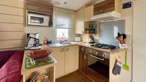 Una cocina compacta con microondas, estufa, fregadero y armarios de madera.