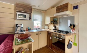 Eine kleine Küche mit Mikrowelle, Herd, Spüle und Holzschränken.
