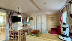 Ein kompakter Wohnbereich mit Essplatz, Fernseher, Ventilator, Uhr und Mikrowelle.