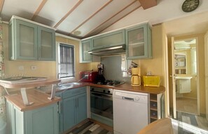 Eine kompakte Küche mit Mikrowelle, Toaster, Kaffeemaschine und Geschirrspüler.