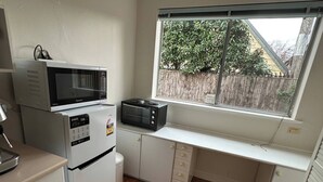 A compact kitchen with a microwave, toaster, and a window with a view of the outside. - Cozy Curtin- 3 guests house (Curtin)