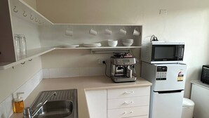 A compact kitchen with a sink, a coffee maker, a microwave, and a refrigerator. - Cozy Curtin- 3 guests house (Curtin)