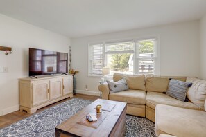 Un salon comprenant un téléviseur, un canapé, une table basse et un tapis à motifs.