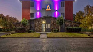 Ein Hotel mit einer Stein-Fassade, einem großen Schild mit der Nummer 6 und violetter Beleuchtung.