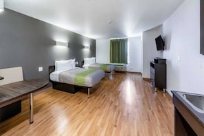 A hotel room with two beds, a desk, a TV, and a window with curtains. - 1 King Bed|NS| Kitchen (San Marcos)