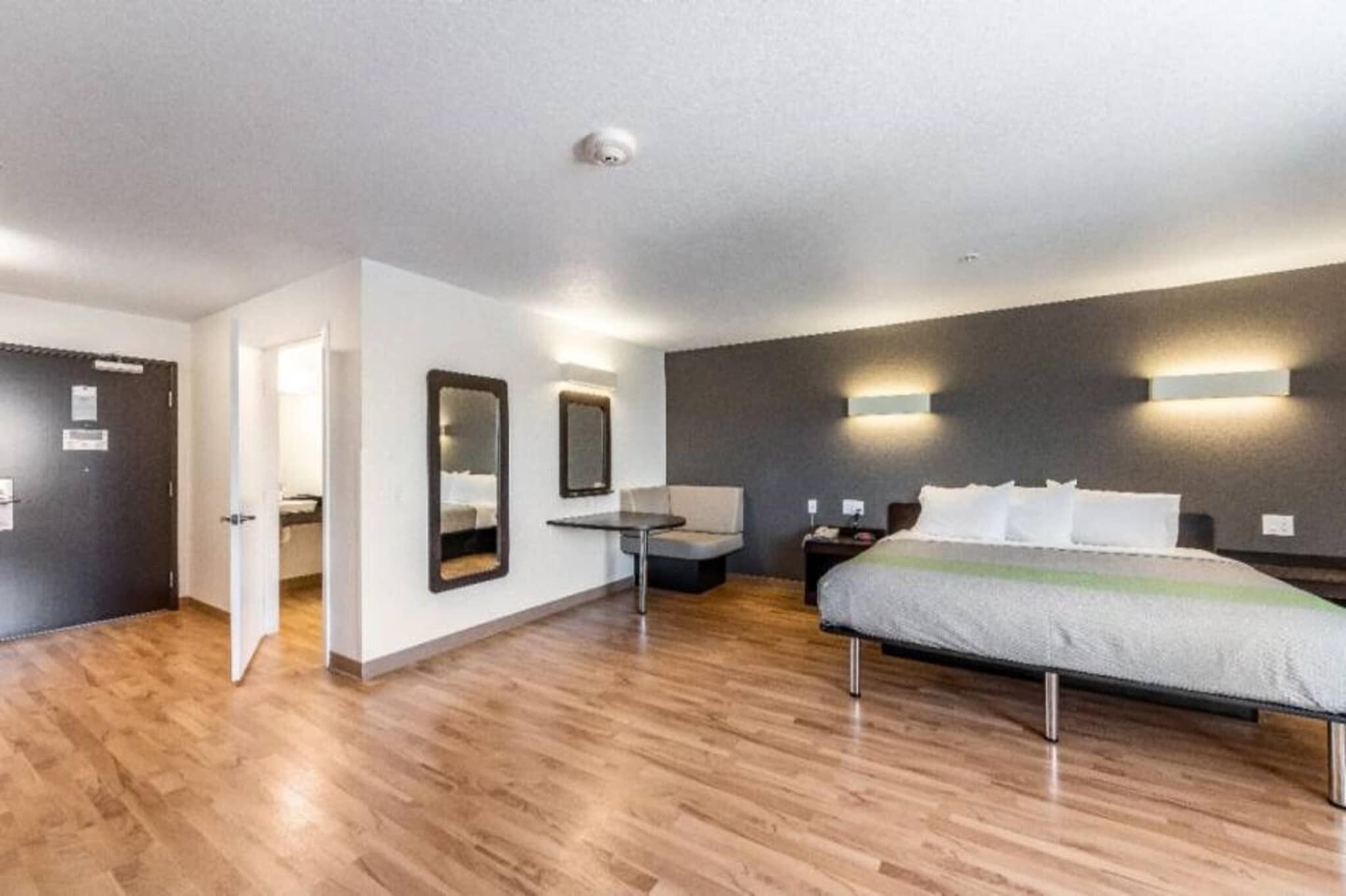Una habitación de hotel con cama, mesita de noche y un espejo en la pared.