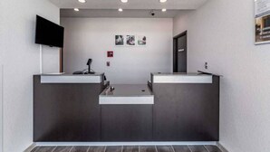 A reception area with a flat-screen TV, a fire alarm, and framed pictures on the wall.