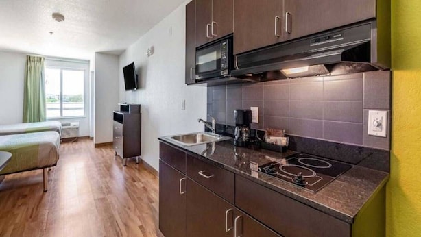 A compact kitchen with a microwave, stove, and sink.