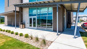 A modern building with a covered entrance, large windows, and a paved walkway.