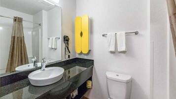 A bathroom with two sinks, a toilet, a mirror, and a towel rack.