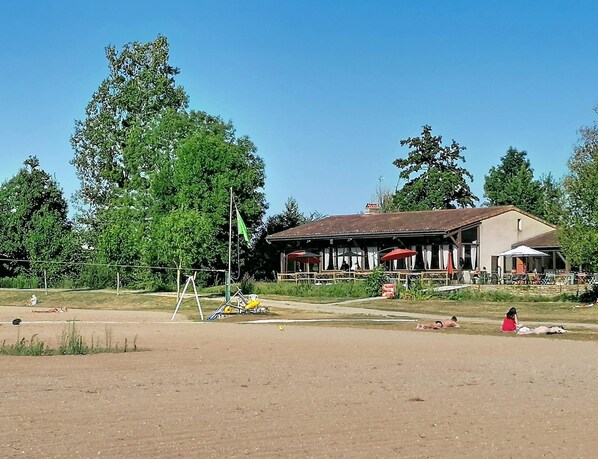A building with outdoor seating, surrounded by trees.