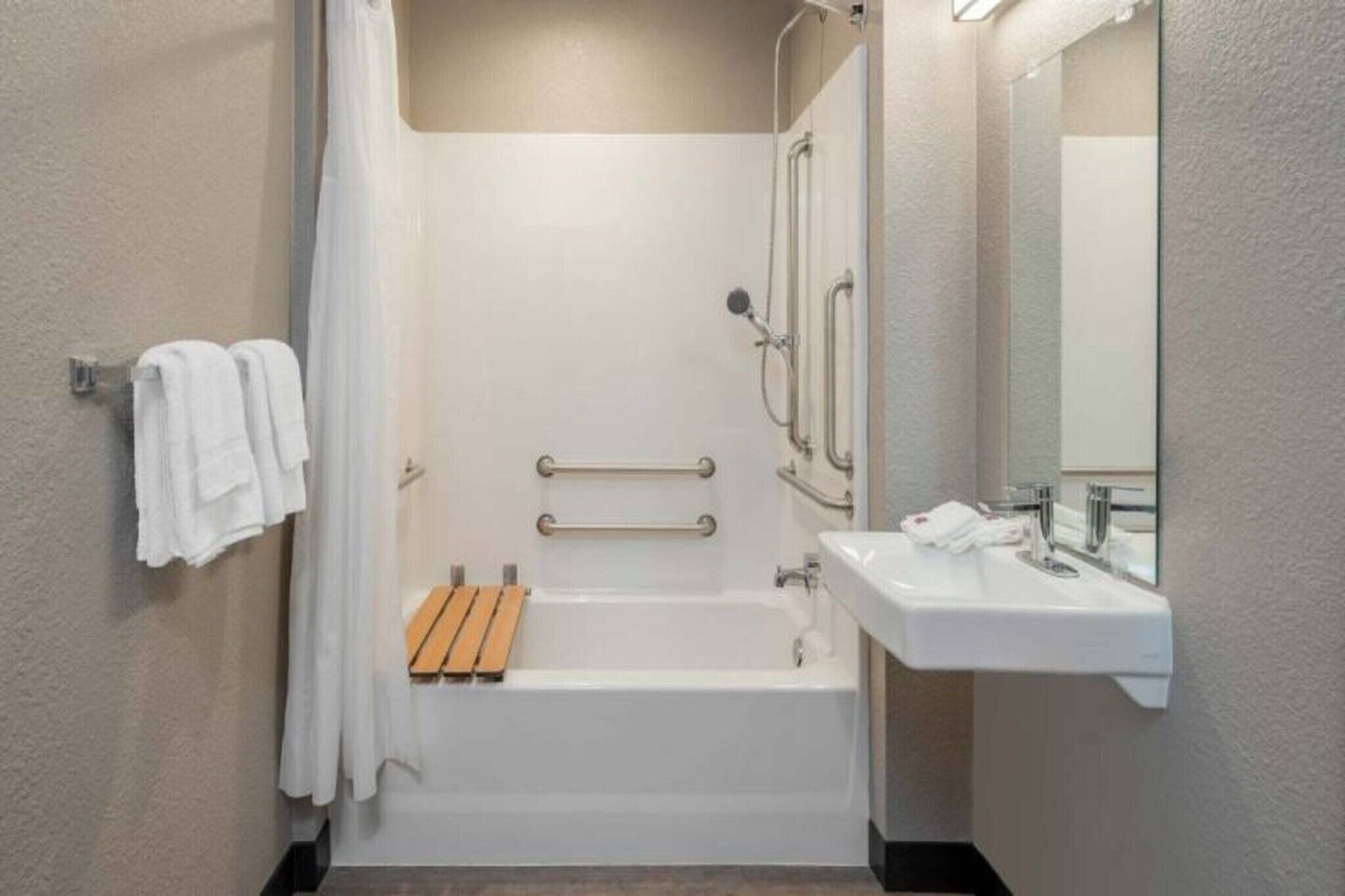 A modern bathroom with a bathtub, shower, and sink.