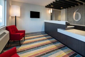 A reception area with a modern design, a red chair, a flat-screen TV, and a number '6' sign on the wall.