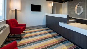 A reception area with a modern design, a red chair, a flat-screen TV, and a number '6' sign on the wall.