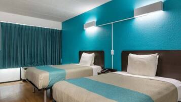 Quarto de hotel com duas camas, paredes verde-água e uma janela com cortinas.