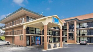 A hotel with a '6' sign, a covered entrance, and a parking lot. - 2 Queen Beds | Non-Smoking (Macon)