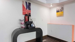 A reception desk with a coffee machine, a glass container, and a poster on the wall. - 2 Queen Beds | Non-Smoking (Macon)